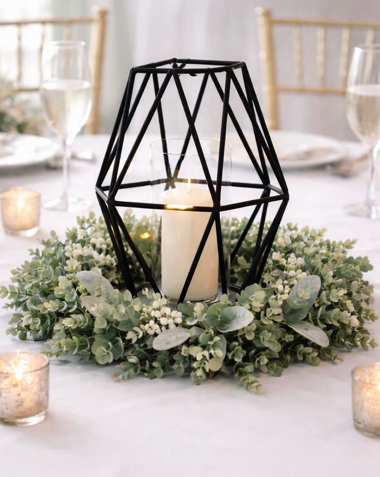 Tall table centerpiece with soft florals, candlelight, and layered event decor textures.