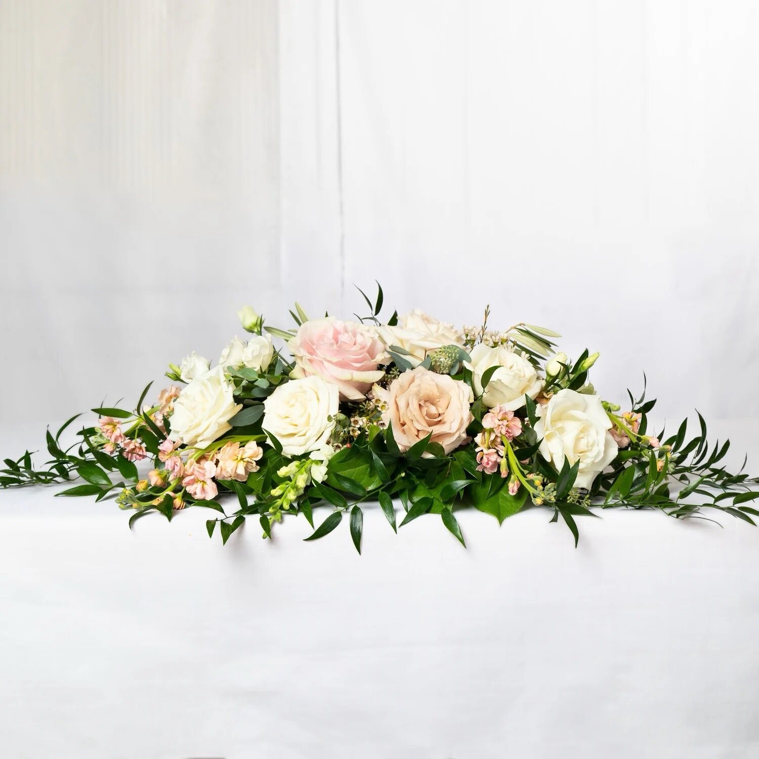 Square centerpiece detail with florals, greenery, and warm layered styling for an event table.