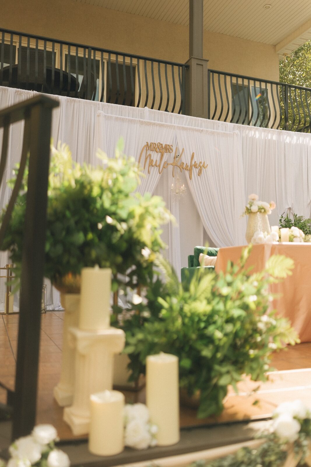 An elegant wedding backdrop with candles, greenery, and personalized Mr. and Mrs. signage designed by House of Ofa.