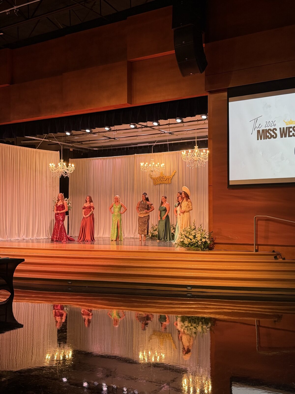 Contestants on stage during Miss West Valley City with House of Ofa event decor and floral staging.