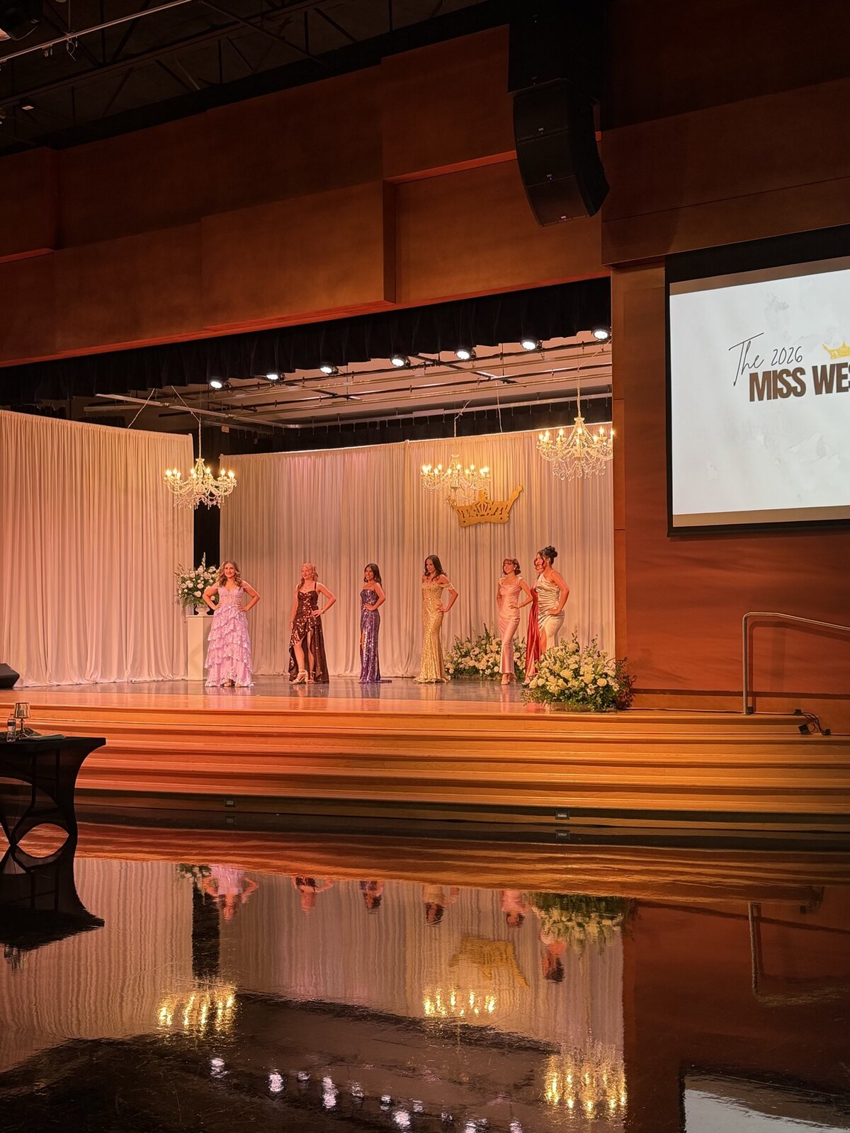 Wide stage view from the Miss West Valley City event with floral accents and warm event lighting.
