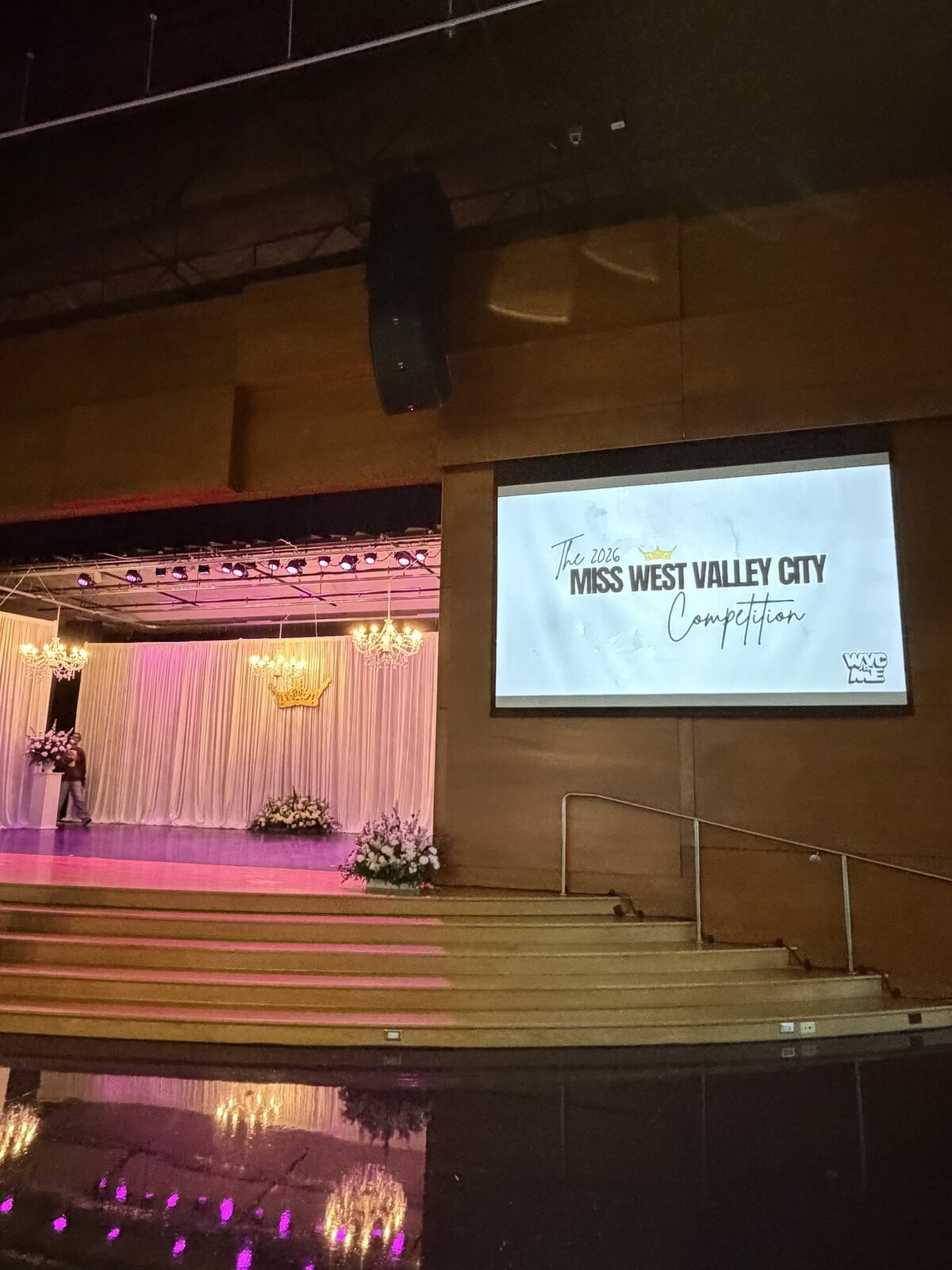 Auditorium view of the Miss West Valley City stage setup with screen signage and decorated backdrop.