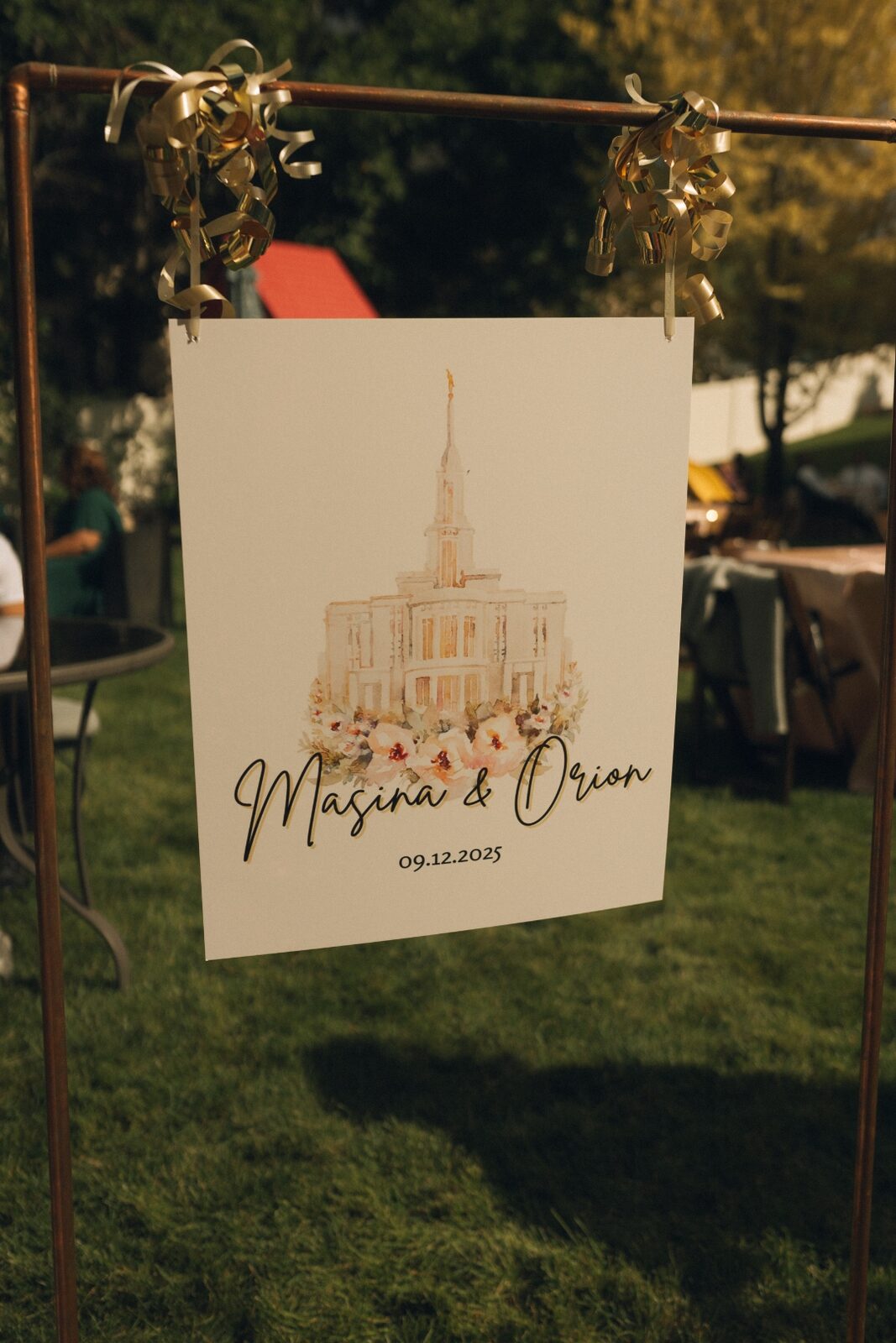 Hand-painted welcome signage with watercolor temple illustration suspended on a copper frame.